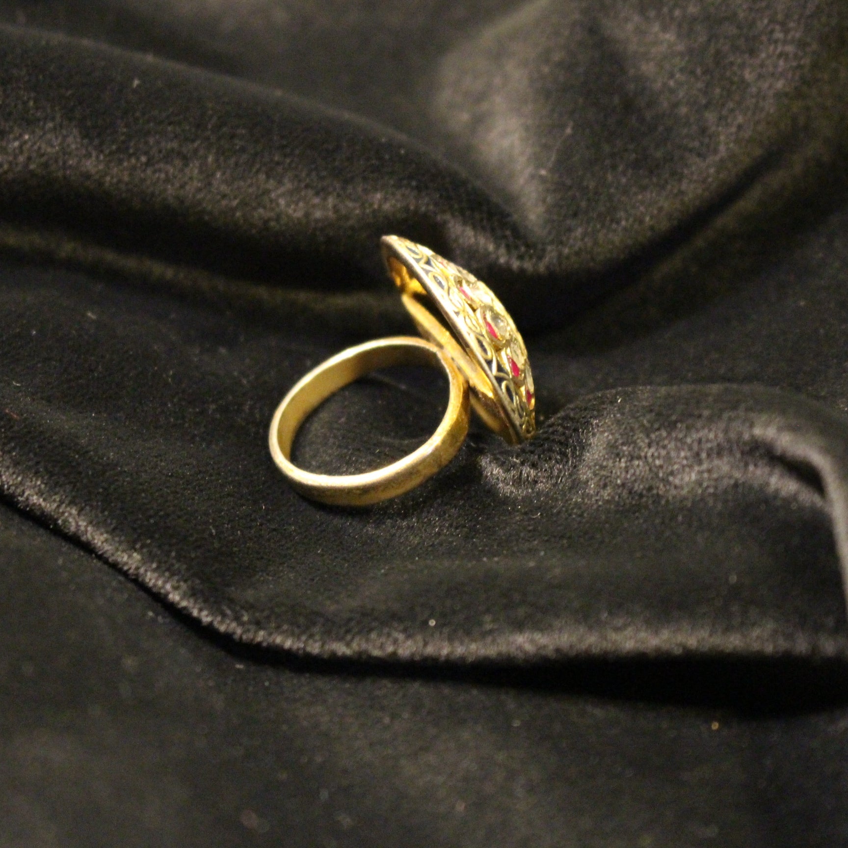 Gold ring with gemstones on a black velvet background