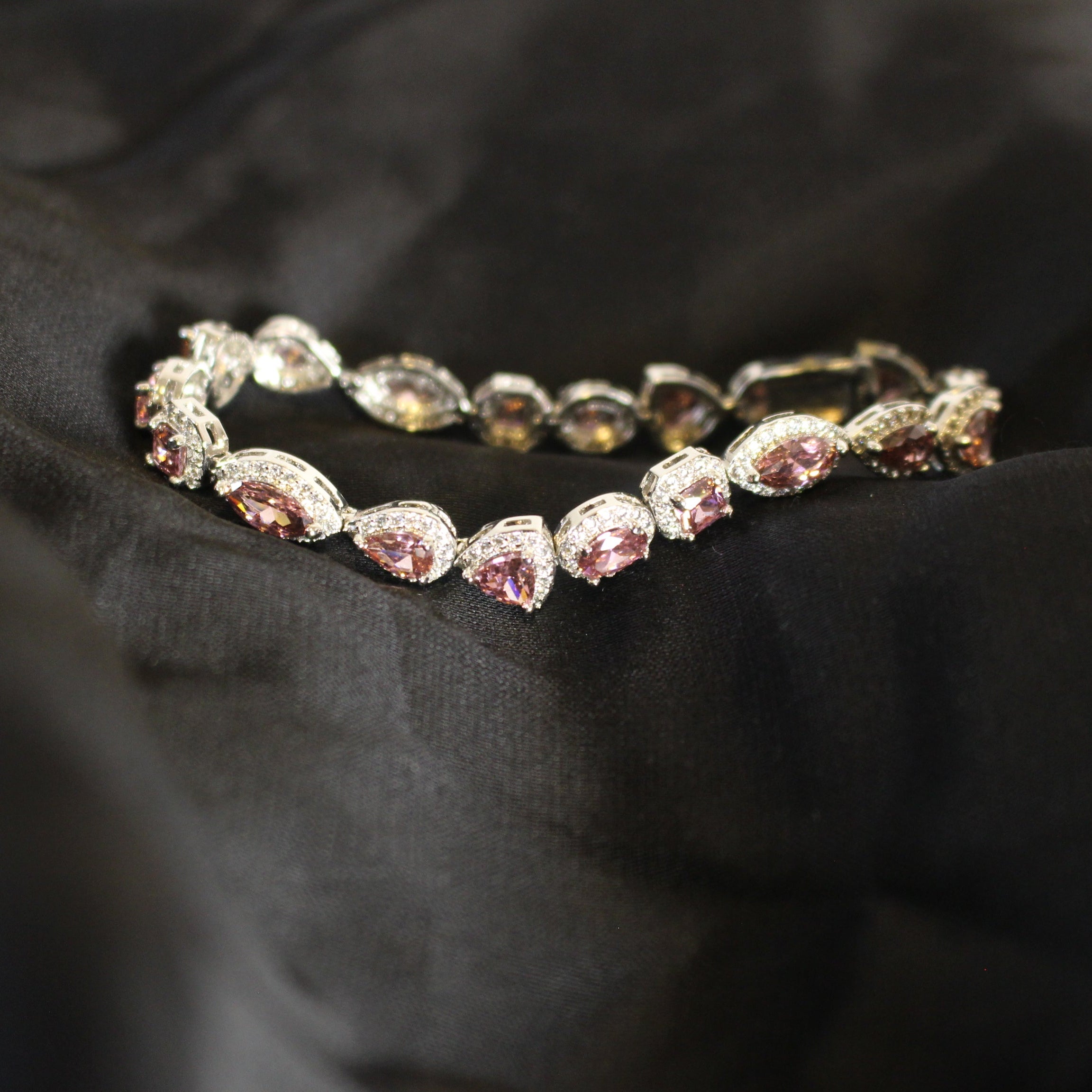 Bracelet with pink gemstones on a black fabric background