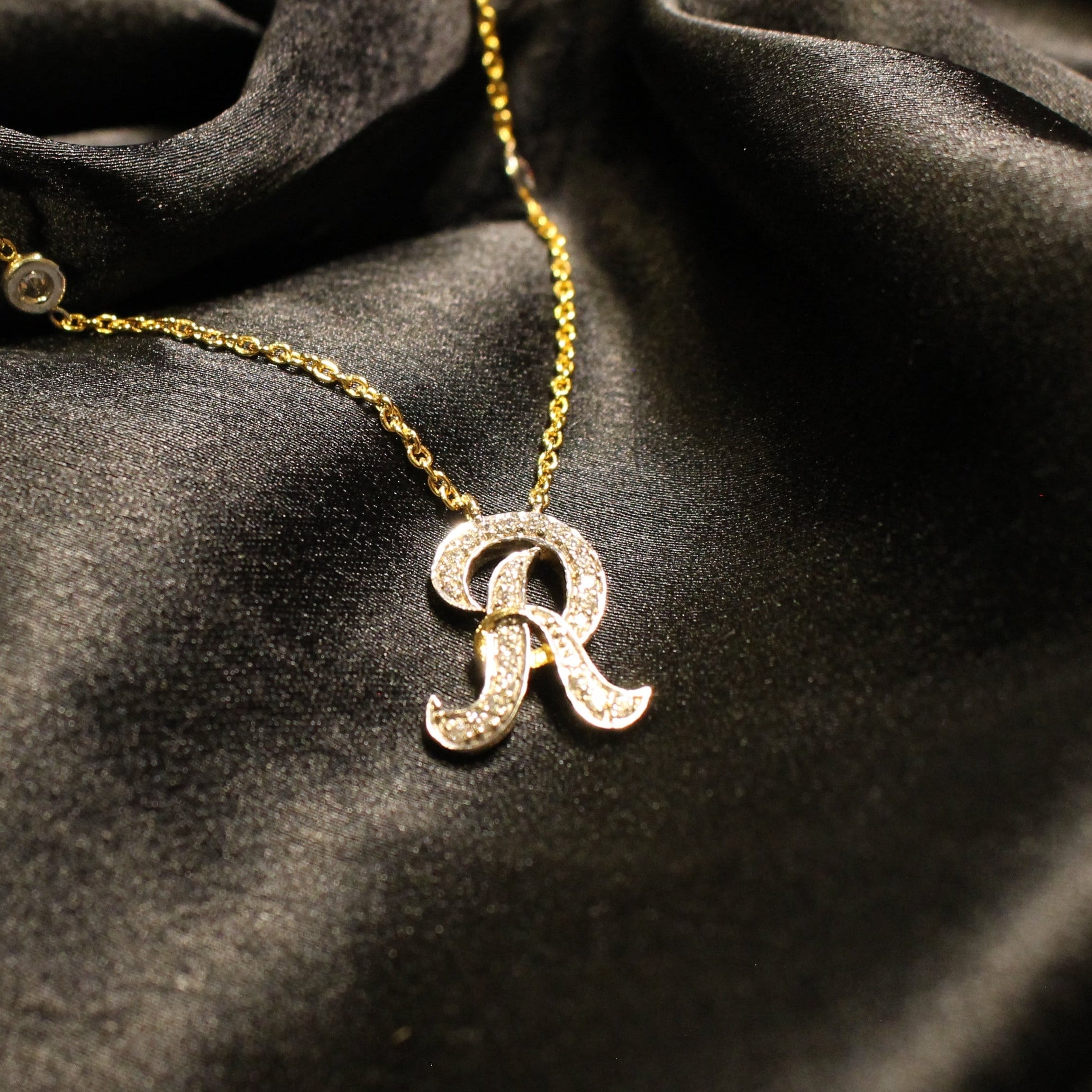 Gold necklace with a 'R' pendant on black fabric